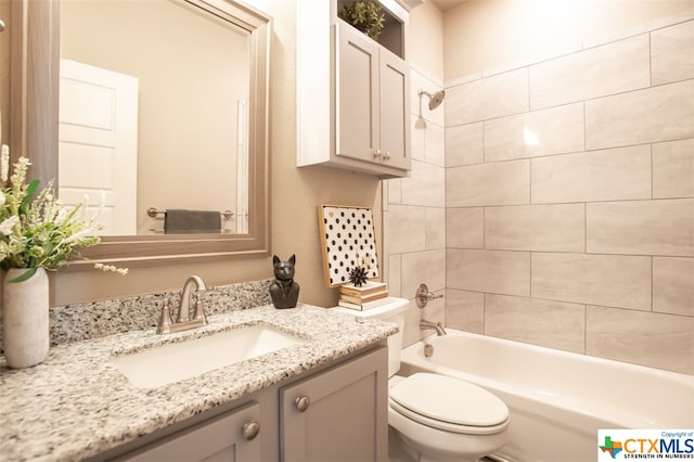 full bathroom featuring tiled shower / bath, toilet, and vanity