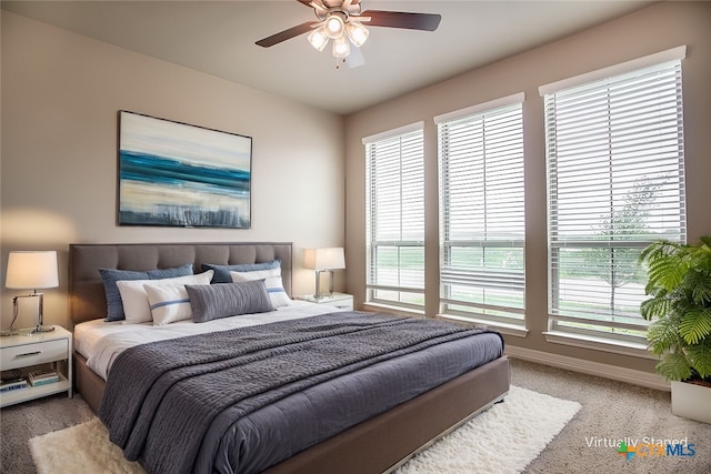 bedroom with multiple windows, light colored carpet, and ceiling fan