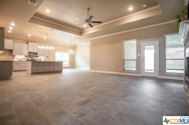 1018 Winchester Dr, Nolanville, TX 76559 - unfurnished living room with a tray ceiling, ceiling fan, a chandelier, baseboards, and ornamental molding