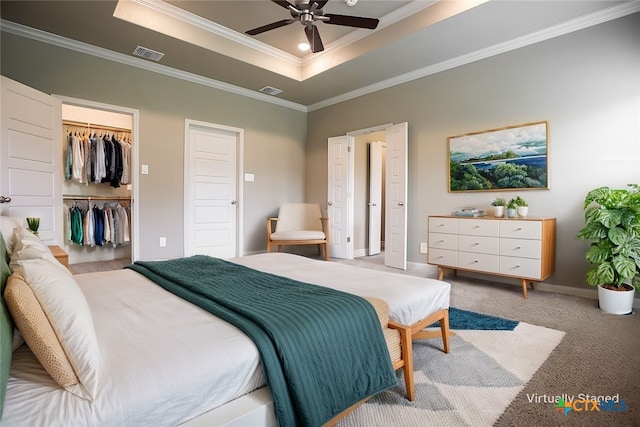 carpeted bedroom featuring ceiling fan, a tray ceiling, and ornamental molding