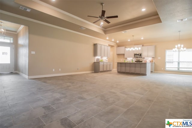 unfurnished living room featuring ornamental molding, ceiling fan with notable chandelier, and a raised ceiling