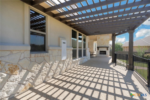 view of patio / terrace featuring an outdoor stone fireplace and a pergola