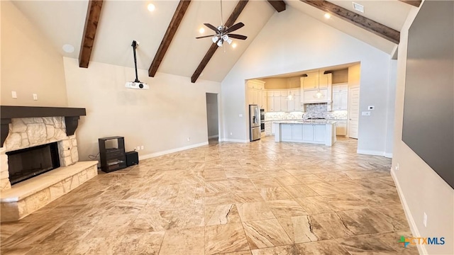 unfurnished living room featuring beam ceiling, a stone fireplace, ceiling fan, and high vaulted ceiling