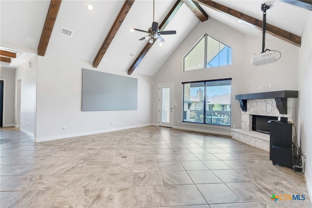 unfurnished living room with beam ceiling, high vaulted ceiling, ceiling fan, and a stone fireplace