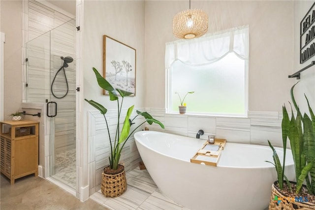 bathroom featuring a freestanding tub, tile walls, and a shower stall