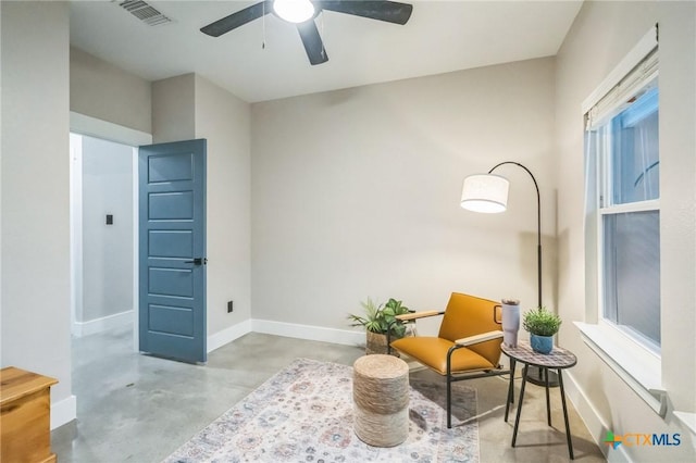 sitting room with baseboards, visible vents, concrete floors, and ceiling fan