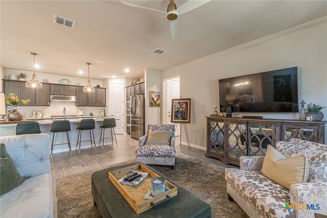 living room featuring hardwood / wood-style flooring, sink, and ceiling fan