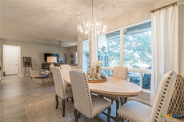 dining area with ceiling fan with notable chandelier and wood-type flooring