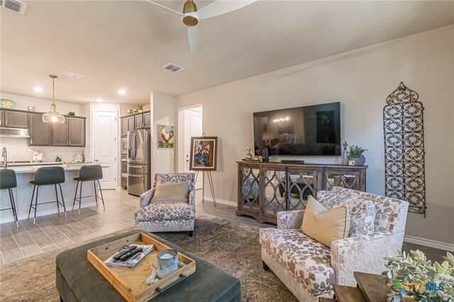 living room featuring ceiling fan, wood-type flooring, and sink