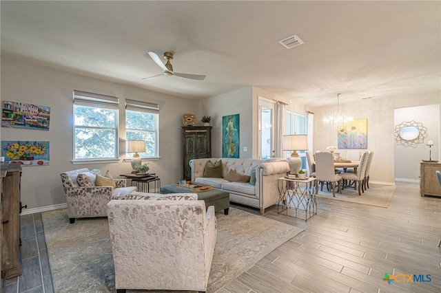 living room featuring ceiling fan with notable chandelier