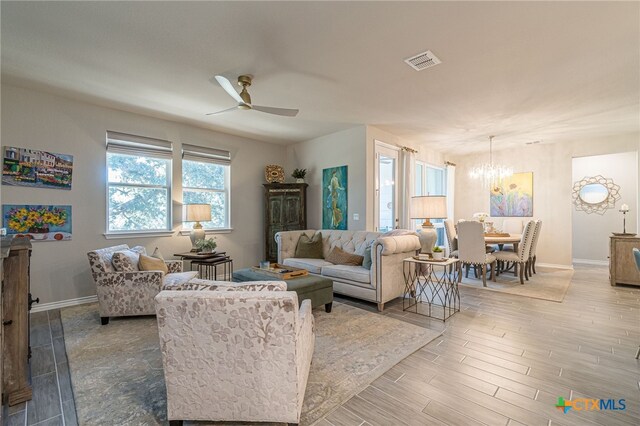 living room with ceiling fan with notable chandelier