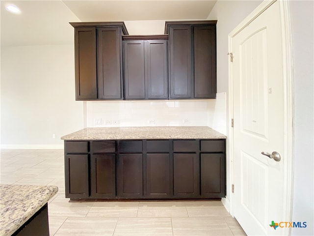 414 Field Corn Ln, San Marcos, TX 78666 - kitchen featuring light stone countertops, dark brown cabinets, and decorative backsplash
