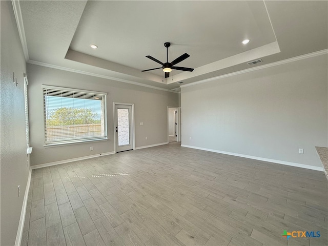 spare room featuring light hardwood / wood-style flooring, ceiling fan, crown molding, and a tray ceiling