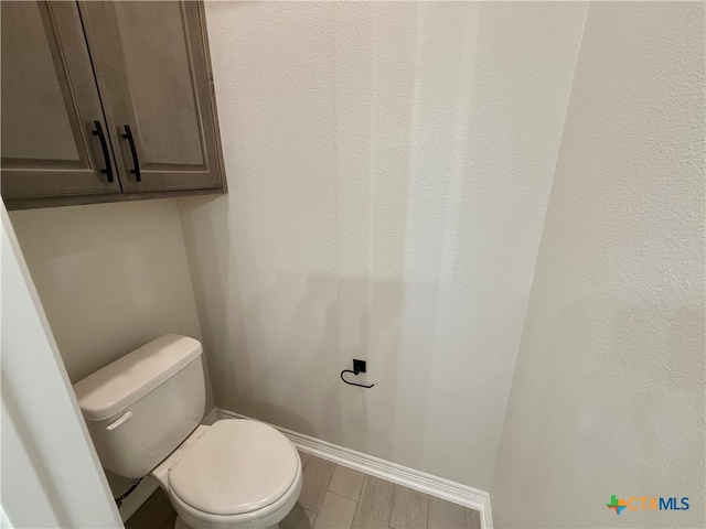 bathroom with toilet and hardwood / wood-style floors