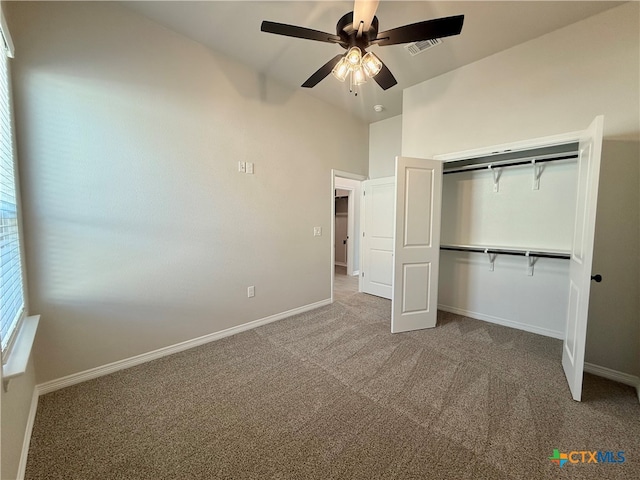 unfurnished bedroom with ceiling fan, a closet, vaulted ceiling, and carpet floors