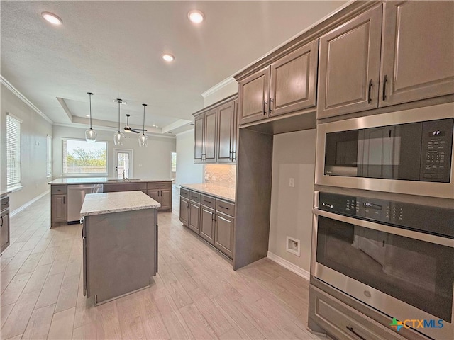 kitchen featuring stainless steel appliances, sink, light stone counters, decorative light fixtures, and a center island