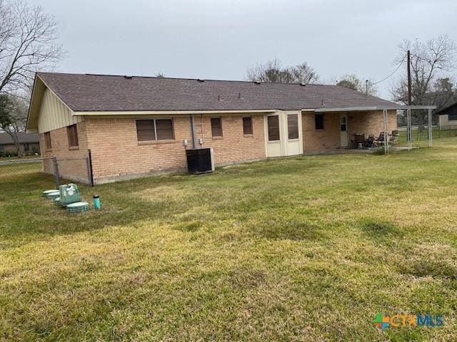 rear view of property with central AC unit and a yard