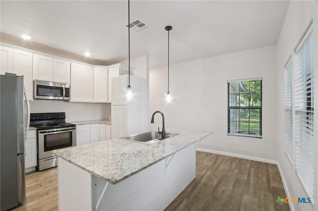 608 E 13th Ave, Belton, TX 76513 - kitchen featuring appliances with stainless steel finishes, light wood-style flooring, white cabinetry, light stone countertops, and hanging light fixtures