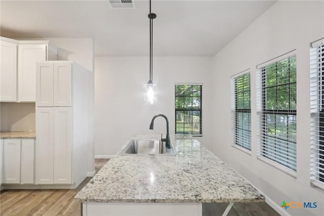 608 E 13th Ave, Belton, TX 76513 - kitchen with light wood-type flooring, white cabinets, a center island with sink, and pendant lighting