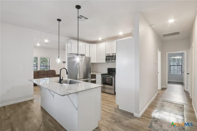 608 E 13th Ave, Belton, TX 76513 - kitchen featuring appliances with stainless steel finishes, white cabinetry, light wood finished floors, light stone countertops, and pendant lighting