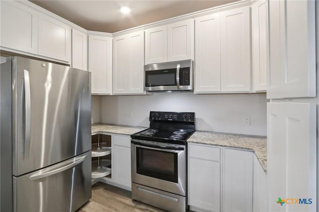 608 E 13th Ave, Belton, TX 76513 - kitchen featuring stainless steel appliances, white cabinets, light wood-type flooring, and light stone counters