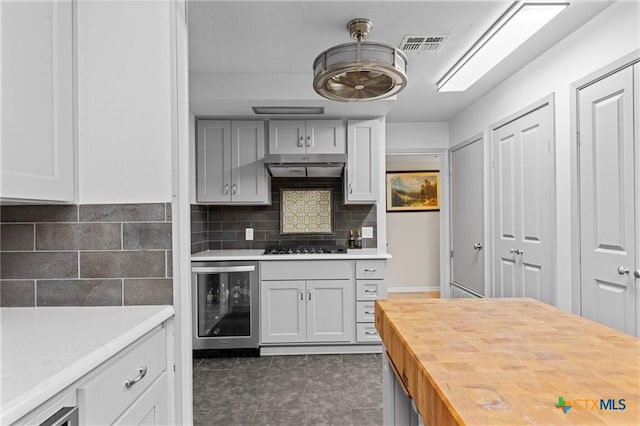 3921 Cripple Creek Dr, Temple, TX 76502 - kitchen featuring beverage cooler, wooden counters, under cabinet range hood, decorative backsplash, and dark tile patterned floors