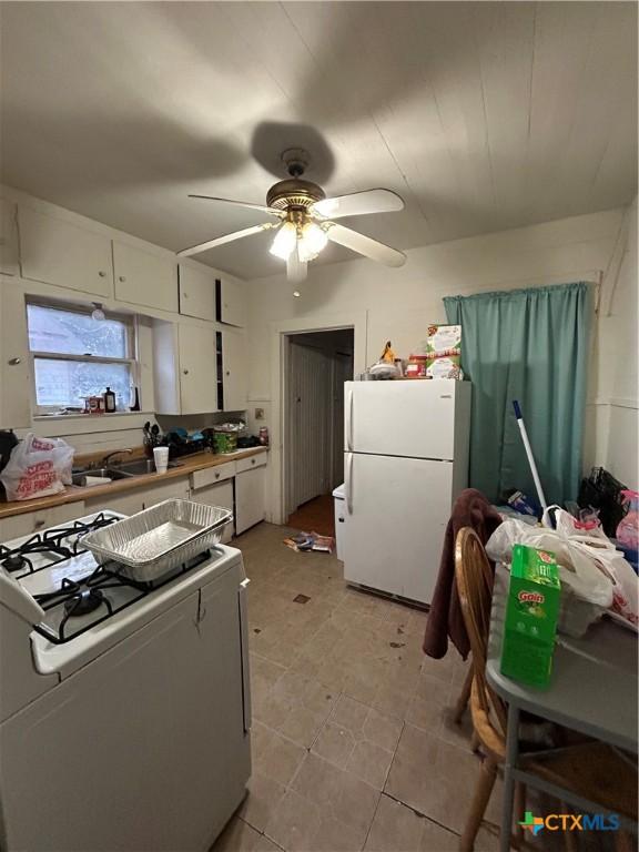 kitchen with white appliances, a sink, a ceiling fan, and white cabinets