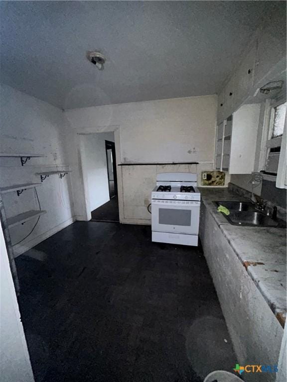 kitchen with white cabinetry, a sink, a textured ceiling, and white gas range