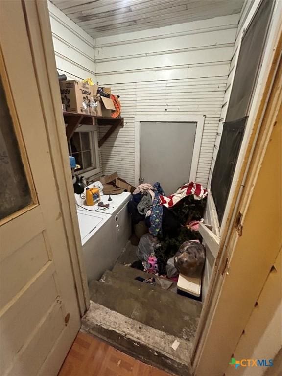 clothes washing area with wooden ceiling, washing machine and dryer, wood walls, wood finished floors, and laundry area