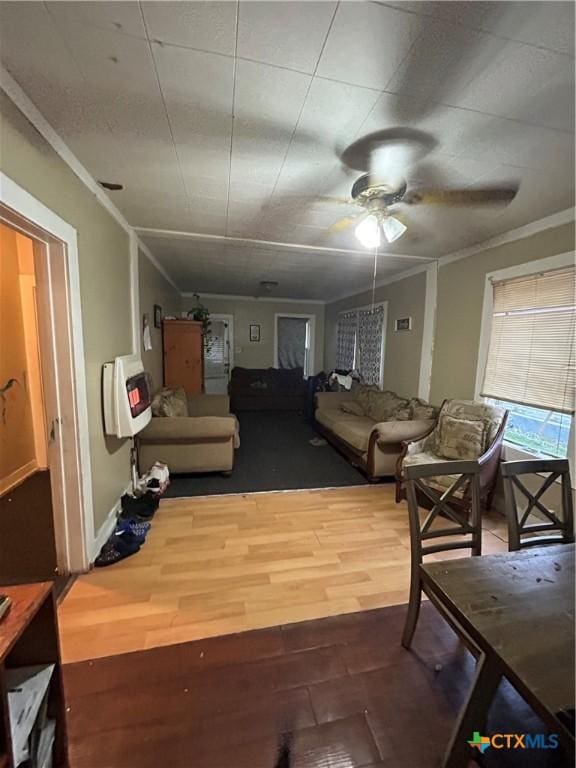 living room with ornamental molding, ceiling fan, heating unit, and wood finished floors