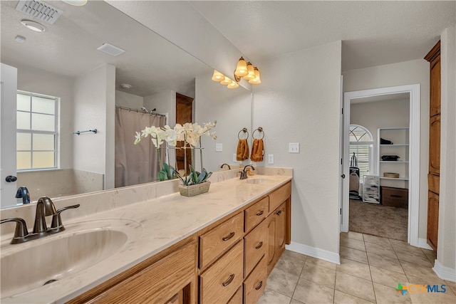 bathroom with tile patterned floors, vanity, a textured ceiling, and walk in shower