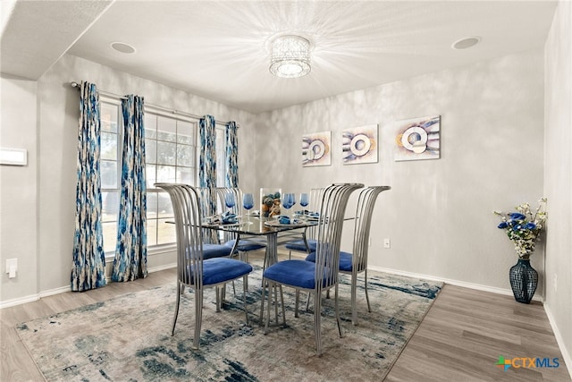 dining area with wood-type flooring and an inviting chandelier