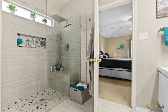 bathroom with tiled shower and ceiling fan