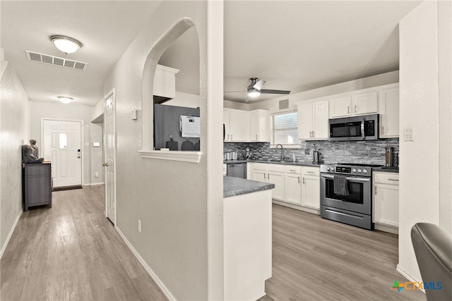 kitchen with ceiling fan, sink, backsplash, white cabinets, and appliances with stainless steel finishes