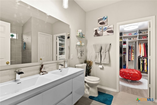 bathroom featuring vanity, toilet, and a tile shower