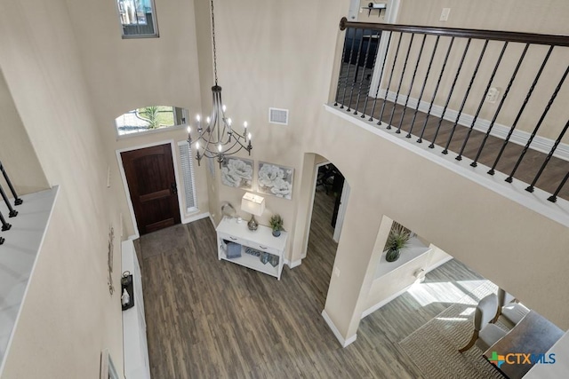 foyer with arched walkways, visible vents, a high ceiling, and wood finished floors