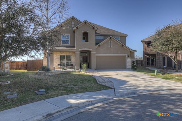 traditional home featuring fence, a shingled roof, stucco siding, concrete driveway, and a front lawn