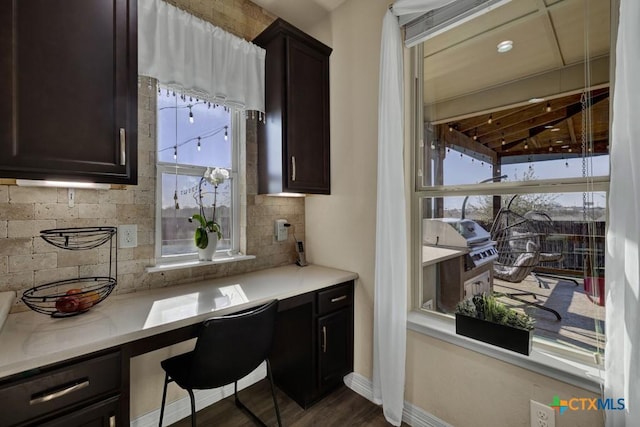 kitchen featuring light countertops, baseboards, backsplash, and built in study area