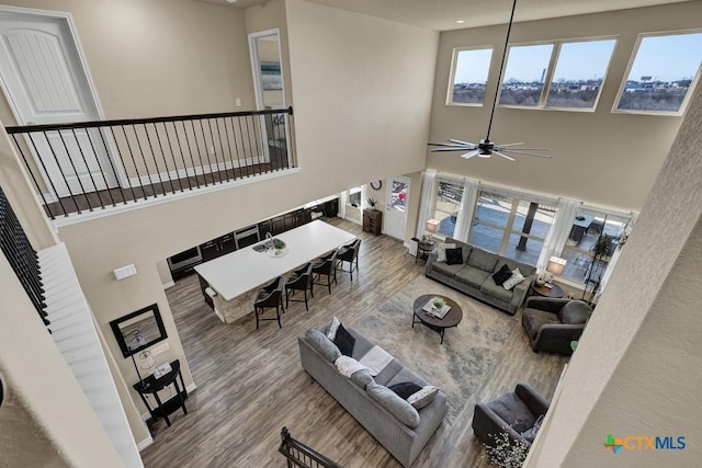 living area with wood finished floors, a towering ceiling, and ceiling fan