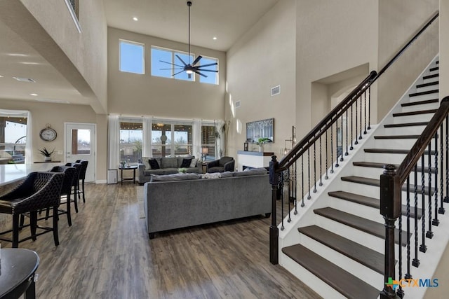 living room with stairway, a healthy amount of sunlight, a ceiling fan, and wood finished floors