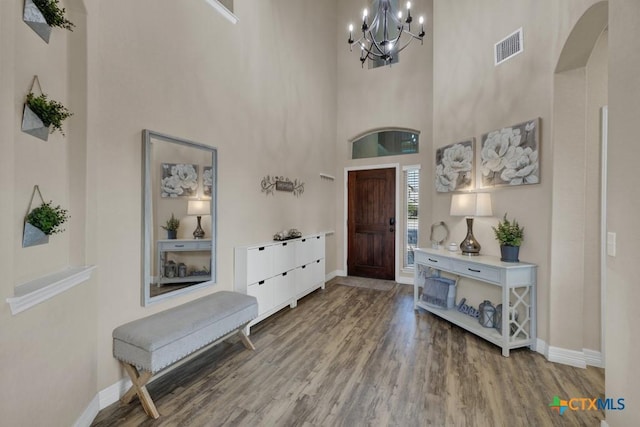 entrance foyer featuring arched walkways, baseboards, an inviting chandelier, and wood finished floors