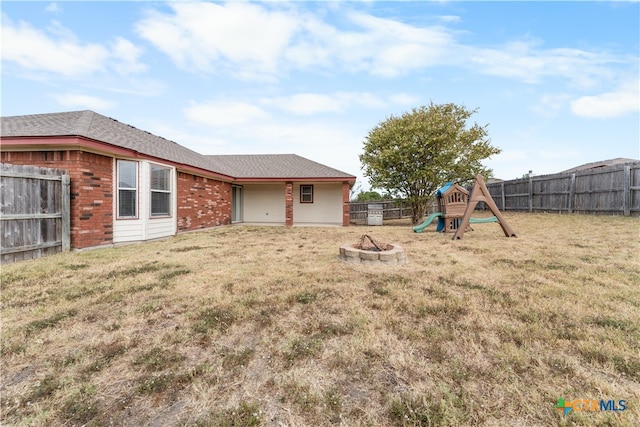 view of yard with an outdoor fire pit, a playground, and a fenced backyard