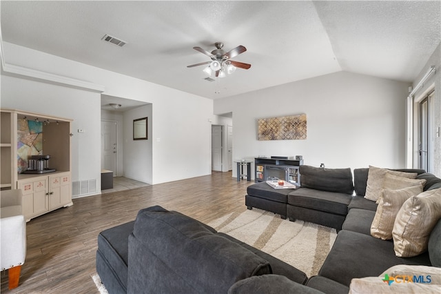 living area featuring ceiling fan, visible vents, wood finished floors, and vaulted ceiling