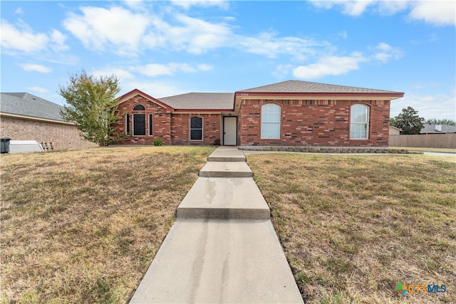 view of front of home featuring a front lawn, fence, and brick siding