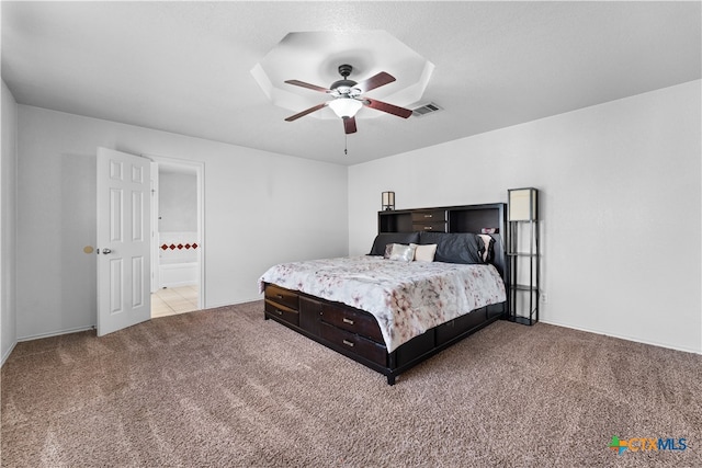 carpeted bedroom featuring ensuite bath, visible vents, and ceiling fan