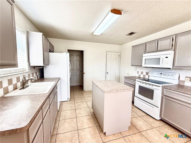 kitchen with backsplash, a center island, light tile patterned floors, white appliances, and a sink