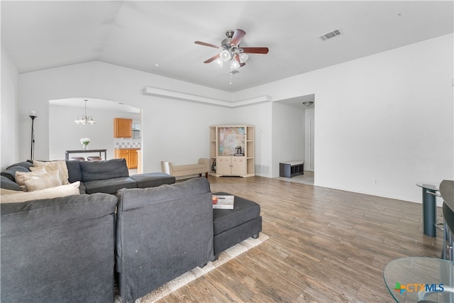 living room featuring visible vents, lofted ceiling, ceiling fan with notable chandelier, wood finished floors, and arched walkways