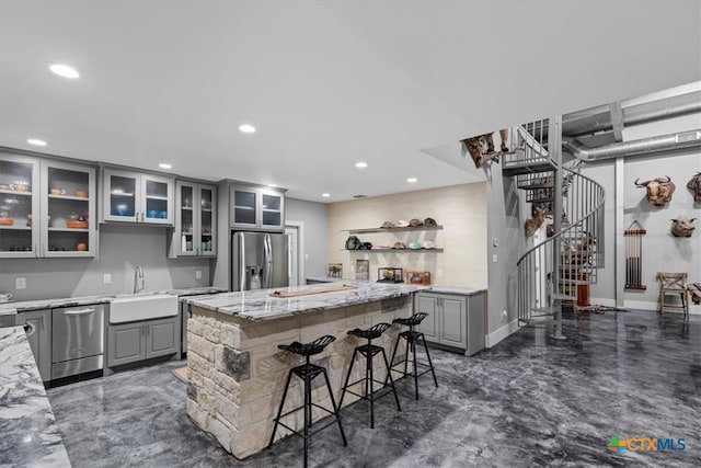 kitchen with stainless steel appliances, gray cabinetry, sink, and a center island