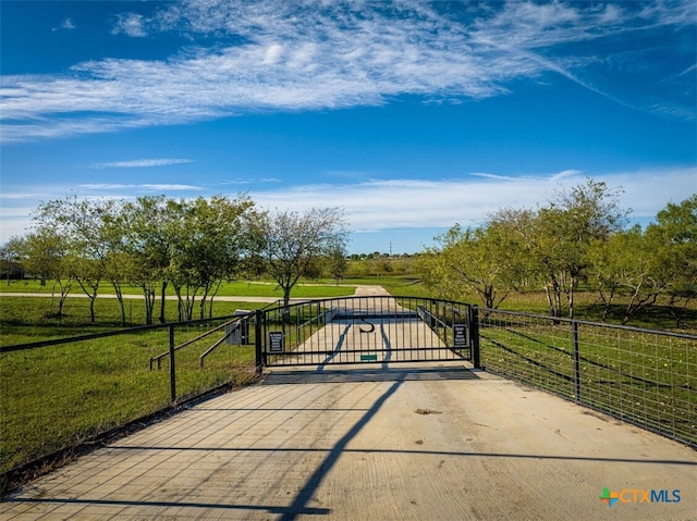 view of gate featuring a rural view and a lawn