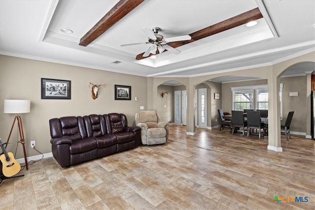 living room with a raised ceiling, light wood-type flooring, and crown molding